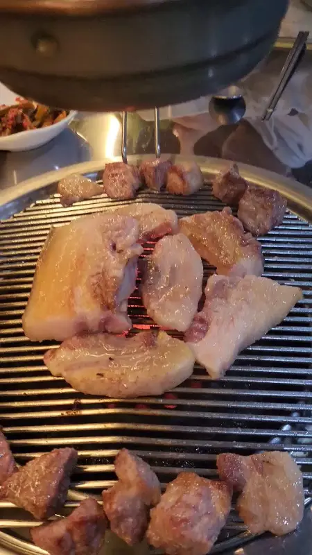 연탄불 위에서 지글지글 익어가는 흑돼지 근고기의 모습