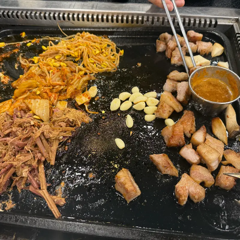 잘 구워진 흑돼지 오겹살과 김치, 콩나물, 고사리가 함께 있는 모습