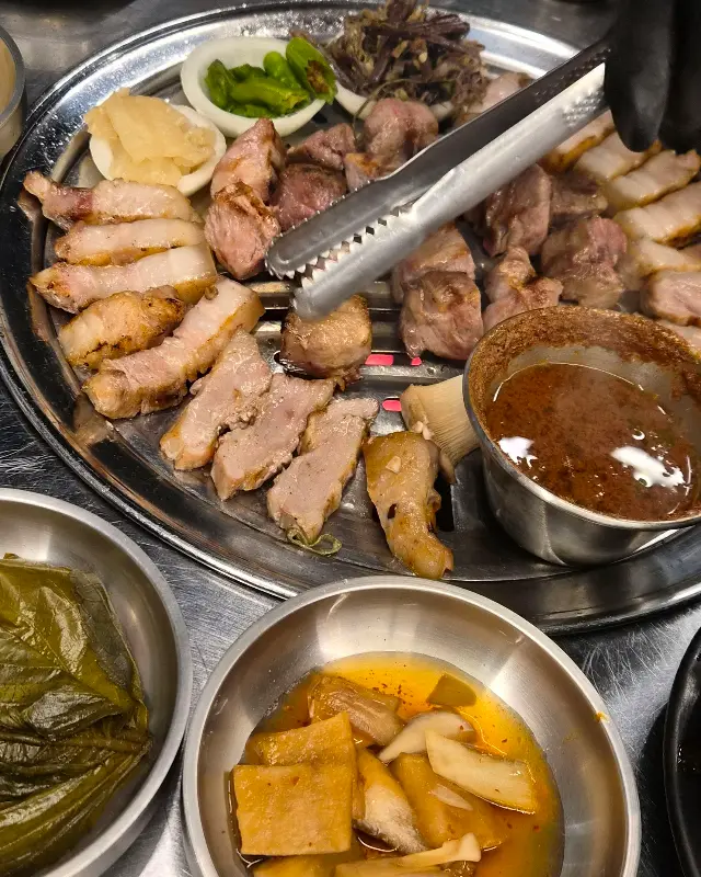 잘 익은 흑돼지를 집게로 들어 올리는 모습