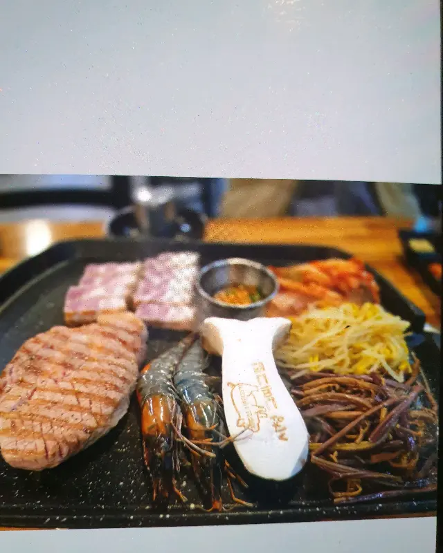 불판 위에 올려진 흑돼지 오겹살, 목살, 새우, 김치, 콩나물, 고사리, 그리고 큼지막한 새송이버섯