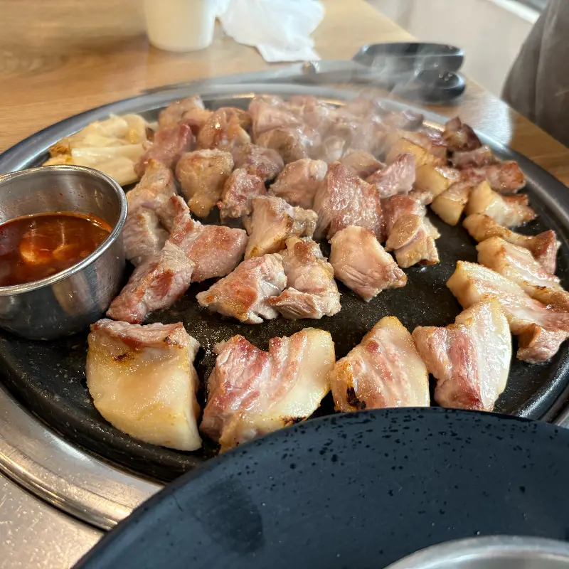 잘 익은 흑돼지 근고기가 먹기 좋게 잘려 불판 위에 놓여있는 모습