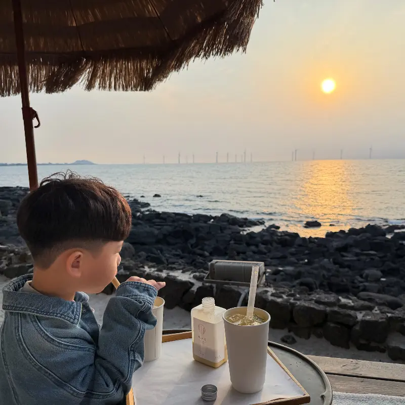 파라솔 아래서 음료를 즐기는 아이