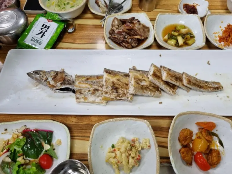 통갈치구이와 다양한 밑반찬들로 가득찬 테이블