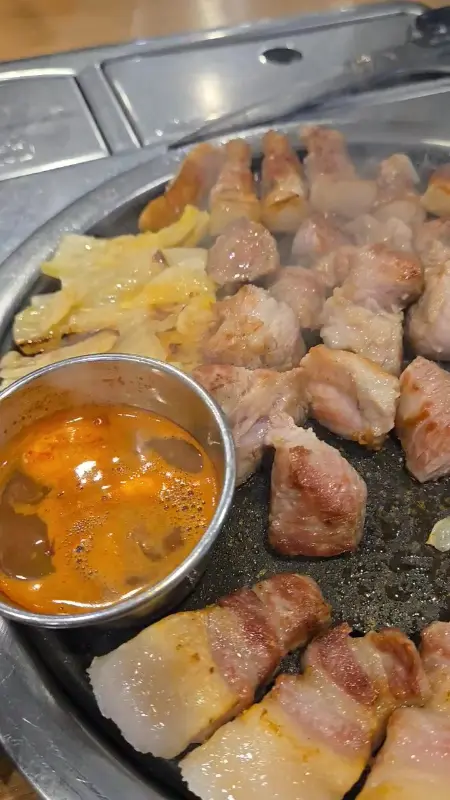 불판 위에 놓여진 흑돼지 근고기와 구워진 백김치의 영상 썸네일