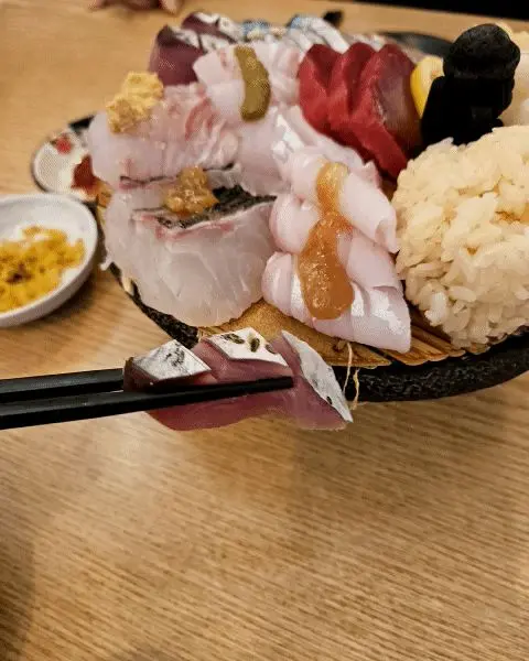 맛있는 모듬회를 젓가락으로 들어올리는 모습