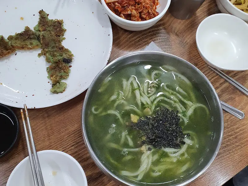 테이블 위에 놓인 보말칼국수, 보말전, 그리고 밑반찬