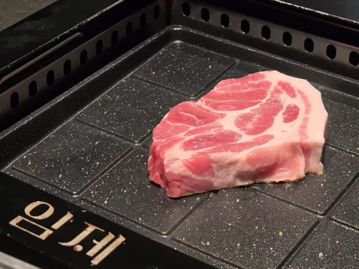 새하얀 불판 위에 올려진 두툼한 흑돼지 덩어리