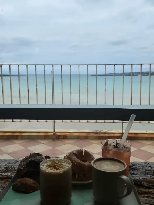 바다를 배경으로 놓인 커피와 음료, 빵