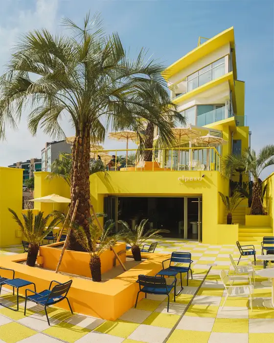 노란색 외벽과 야자수가 돋보이는 건물 전경