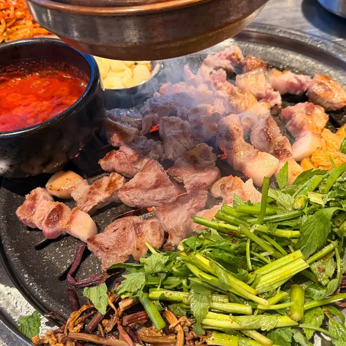 잘 익은 흑돼지와 곁들여 먹을 신선한 채소들이 한가득 올려진 불판