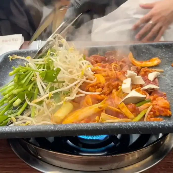 잘 달궈진 불판 위에서 구워지고 있는 오리로스와 주물럭, 채소들