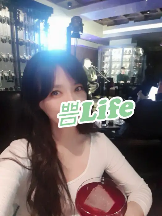 재즈 공연을 배경으로 칵테일을 들고 있는 여성