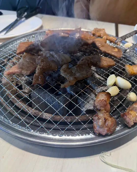 다양한 고기와 쌈 채소가 불판 위에 구워지고 있는 모습