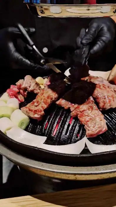 잘 구워진 양갈비 조각을 집게로 집어 옮기는 모습