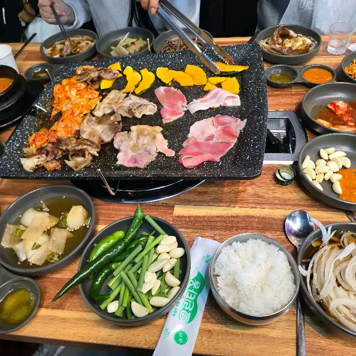 테이블에 차려진 푸짐한 식사 모습, 볶음밥과 찌개, 쌈채소 등이 보인다