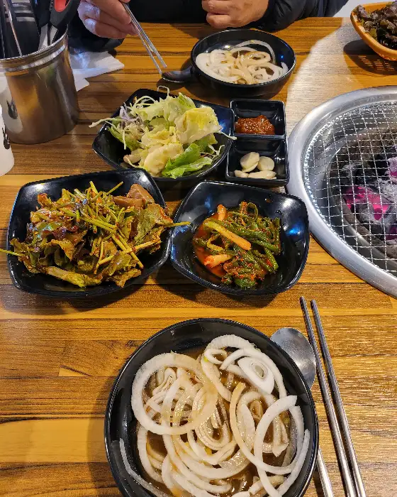테이블에 차려진 푸짐한 반찬들과 솥밥, 그리고 쌈 채소. 정성스럽게 차려진 밥상이 느껴집니다.
