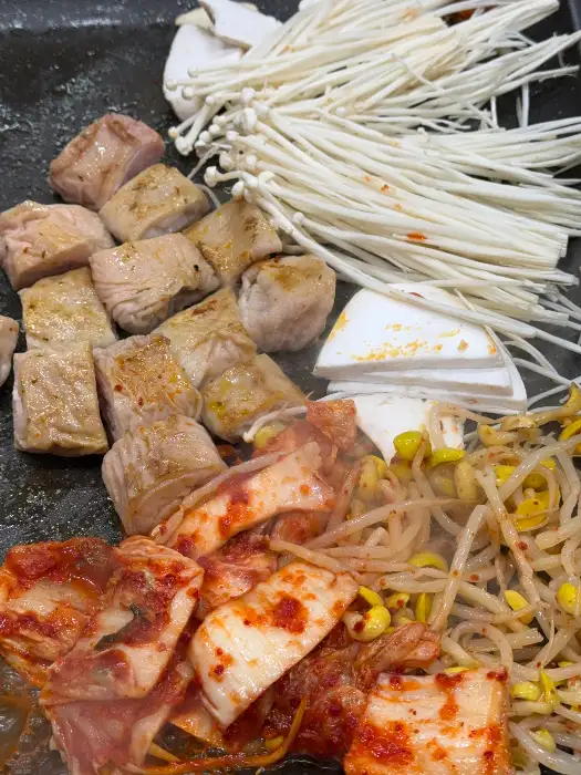 불판 위에서 구워지는 대패삼겹살과 곁들임 메뉴