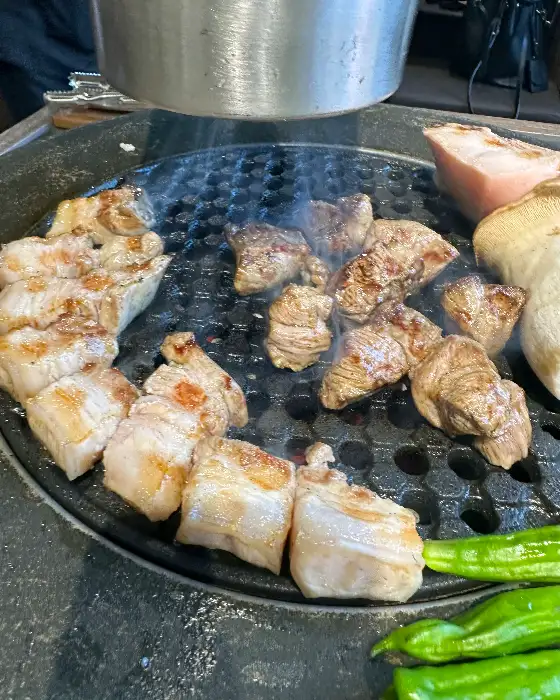 숯불 위에서 지글지글 익고 있는 흑돼지 오겹살과 목살.