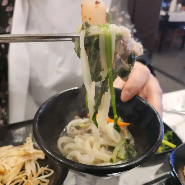 집게로 집어 올린 칼국수와 고기