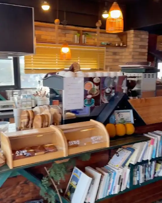 카페 내부 모습, 카운터와 진열된 빵들, 책이 꽂힌 선반