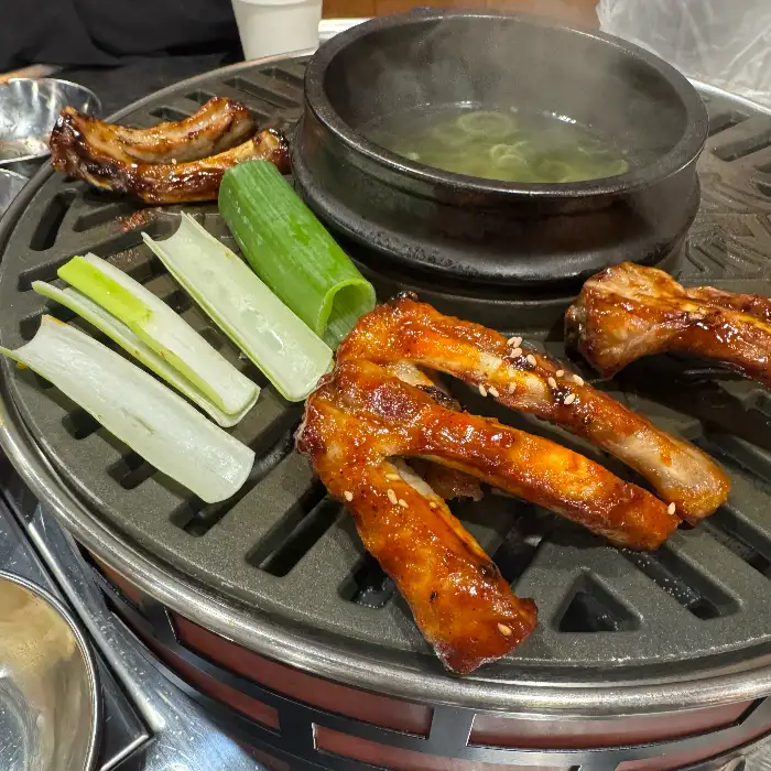 불판 위에 올려진 쪽갈비와 곁들임 채소