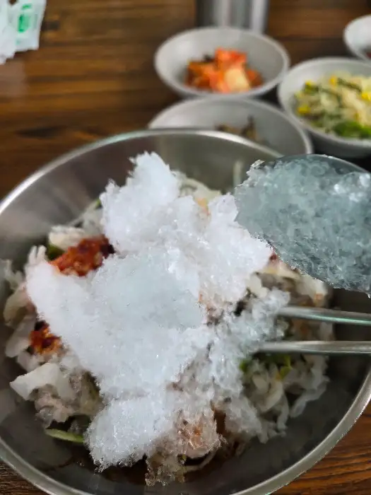물회 위에 직접 갈아낸 얼음을 얹는 모습