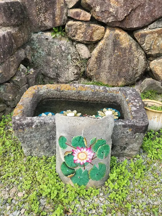 돌담과 돌 항아리, 그리고 연꽃 장식이 있는 카페 외부 모습
