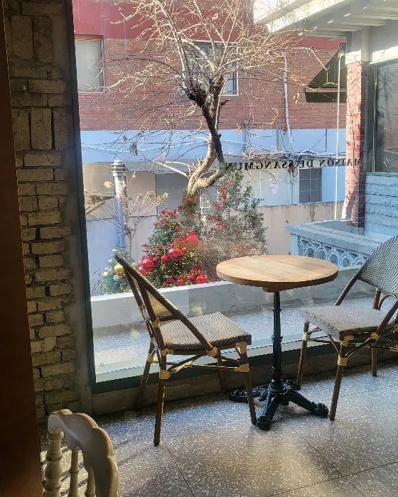 통창 너머로 보이는 테이블과 의자, 그리고 계절감이 느껴지는 나무와 장식들이 조화로운 풍경.