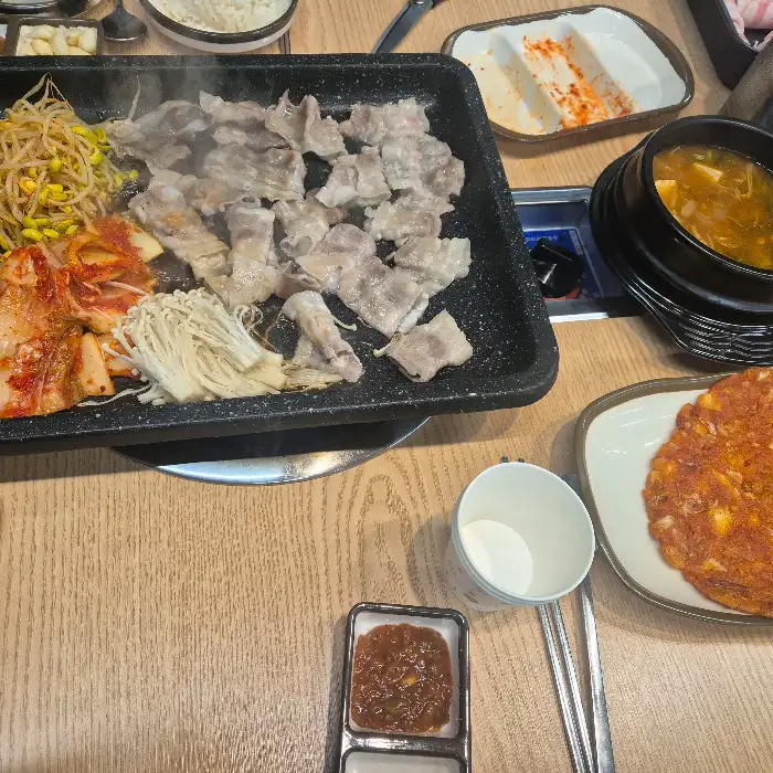 삼겹살과 함께 구워 먹을 김치, 콩나물, 팽이버섯 등 다양한 재료가 준비된 모습