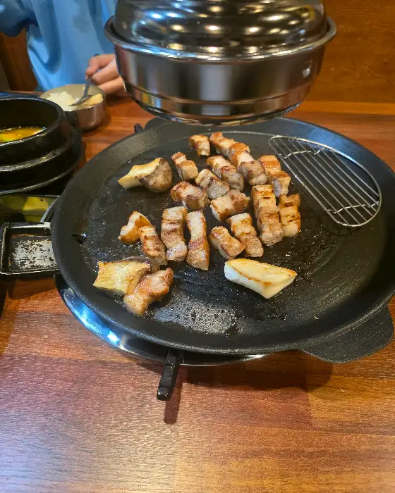 잘 구워진 삼겹살 한 점과 곁들임 찬