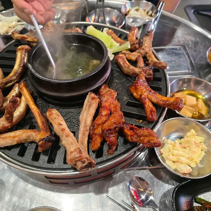 불판 위에서 익어가는 쪽갈비와 곁들임 재료들