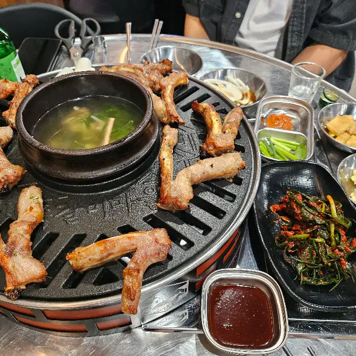 불판 위에 푸짐하게 담긴 쪽갈비와 곁들임 메뉴들