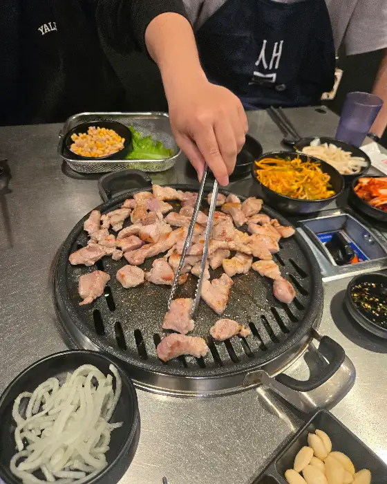 불판 위에서 익어가는 뒷고기와 콩나물, 김치