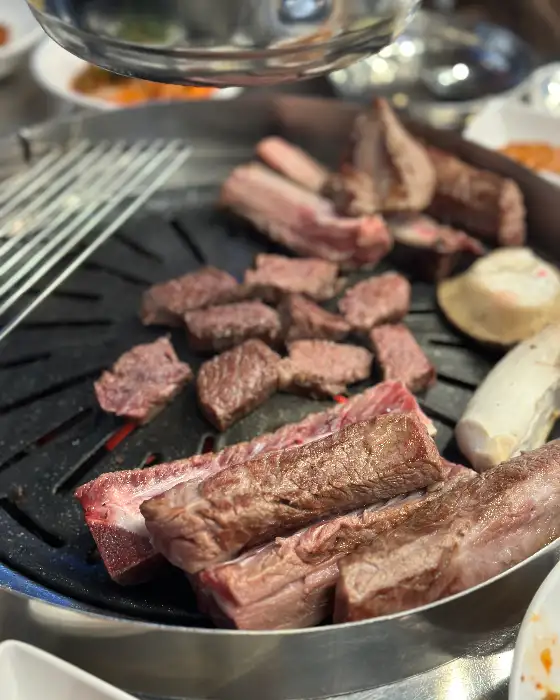 숯불 위에서 구워지고 있는 두툼한 갈비와 버섯