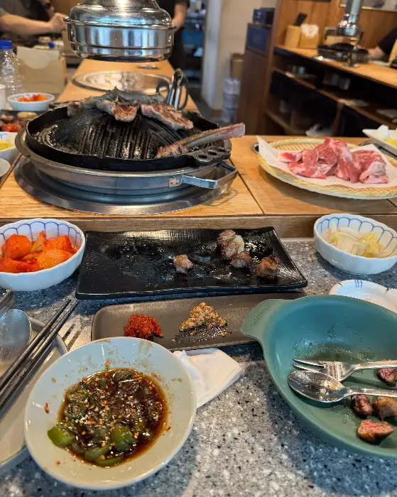 테이블 위에 여러 가지 양갈비 요리와 곁들임 음식이 놓여 있는 모습