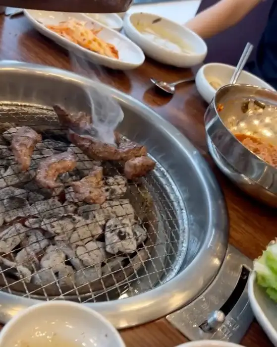 숯불 위에서 연기가 피어오르며 맛있게 익어가는 소갈비살
