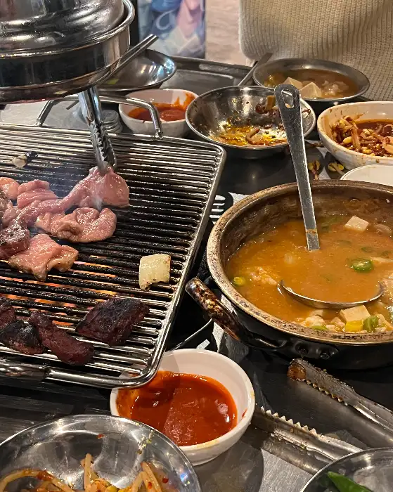 숯불 위에서 익어가는 돼지 부속구이와 곁들임 메뉴들