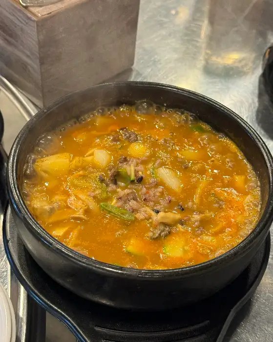 뜨거운 김이 나는 된장찌개가 담긴 검은색 뚝배기