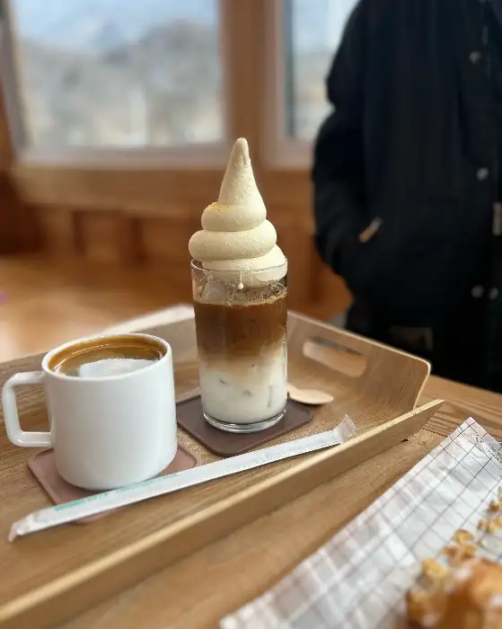 커피 잔과 아이스크림이 담긴 컵이 트레이에 놓여 있다. 아이스크림 위에는 옥수수 모양의 토핑이 올라가 있다.