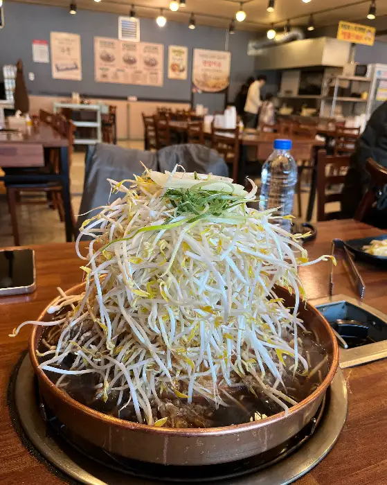 산더미처럼 쌓인 숙주나물 아래 불고기가 있는 불고기 전골