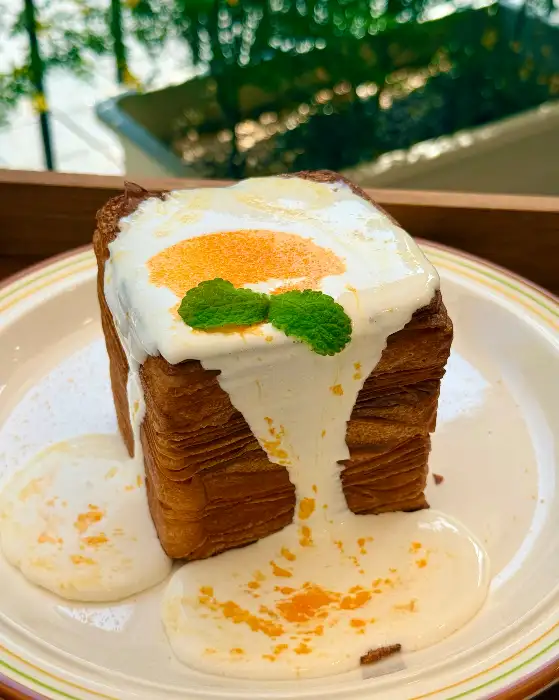 크루아상 빵 위에 달걀 프라이 모양의 크림 토핑