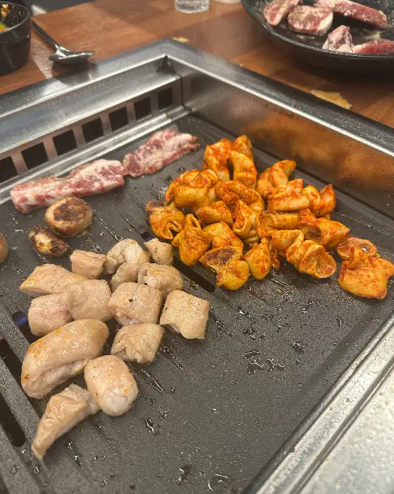 불판 위에 막창, 곱창, 삼겹살 등이 함께 올려져 구워지는 모습