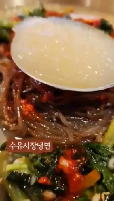 냉면 면발을 젓가락으로 집어 들어 올리는 모습