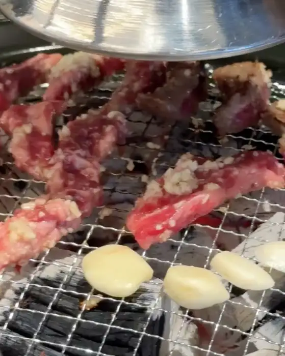 숯불 위에서 익고 있는 마늘 양념 소갈비살과 통마늘