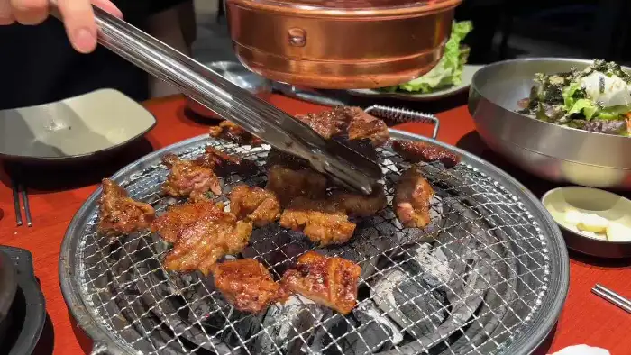 화로 위에서 구워지는 갈비와 곁들임 찬