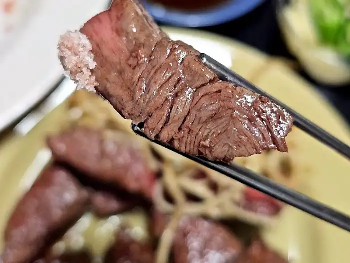집게로 집어 올린 부드러운 스테이크 한 점