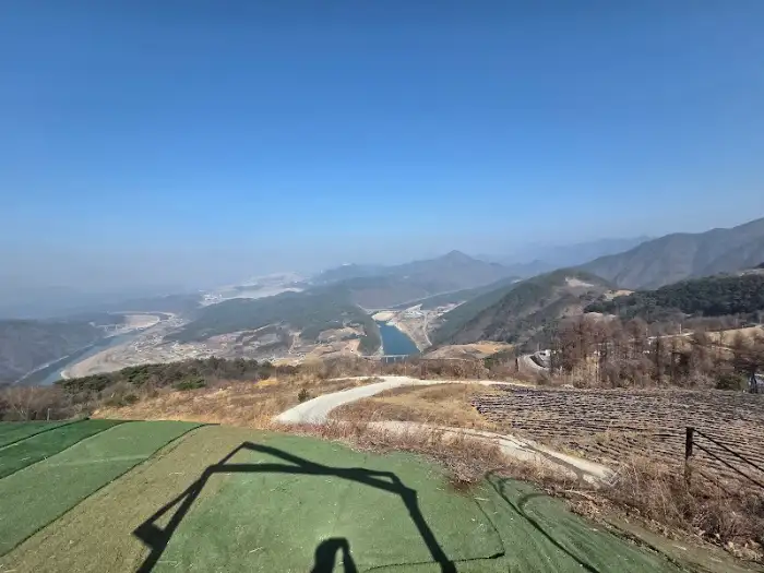 넓은 잔디밭과 산 능선, 강이 보이는 풍경