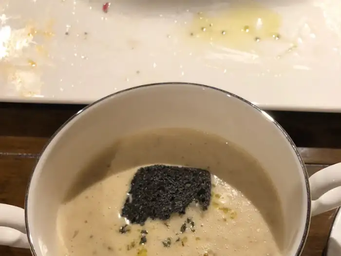 크리미한 수프에 검은색 토핑이 올라간 모습