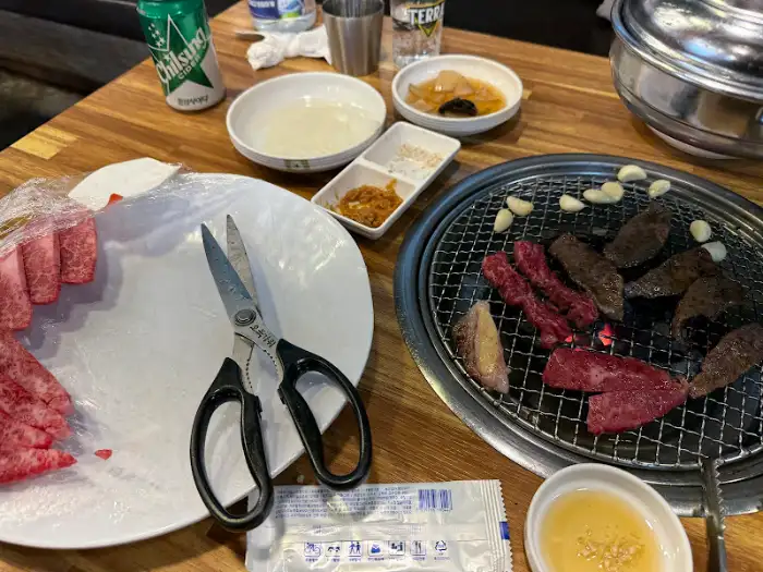 식탁 위 풍경, 숯불 위에 구워지는 고기, 그리고 밑반찬