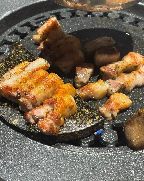불판 위에서 노릇하게 구워지고 있는 삼겹살과 목살